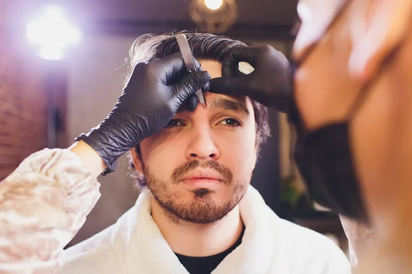 Profissional ajustando sobrancelha masculina